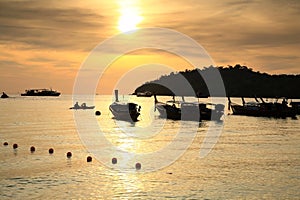 Silhouette people kayak by boats on sea at sunset, Ko Lipe island