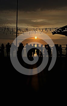 Silhouette of people at a panoramic viewpoint and looking at a beautiful sea, sunset. People unrecognizable.