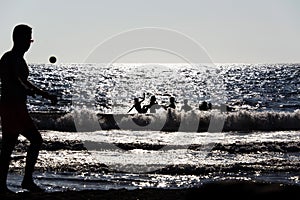 Silhouette of People playing, swimming in the waves in the island of Patmos, Greece in summer time