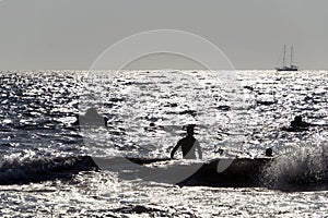 Silhouette of People playing, swimming in the waves in the island of Patmos, Greece in summer time