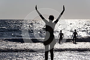 Silhouette of People playing, swimming in the waves in the island of Patmos, Greece in summer time