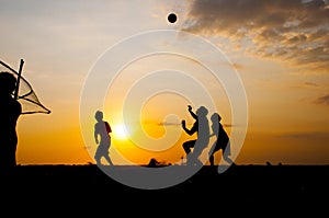 Silhouette of people playing volleyball at beach on the sunset time