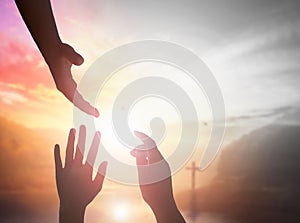 Silhouette people raising hands over blurred the cross on beautiful golden autumn sky sunset background