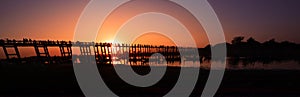 Silhouette of people on U Bein bridge at sunset in Amarapura. Mandalay, Myanmar panorama