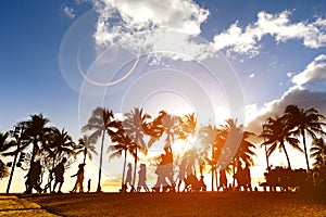 Silhouette of people walking at sunset on crowded Waikiki