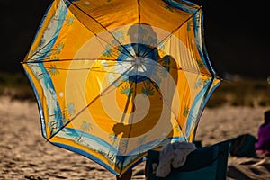 Silhouette of a person behind a beach summer umbrella. Beach sea concept. Colorful yellow summer shade umbrella