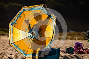 Silhouette of a person behind a beach summer umbrella. Beach sea concept. Colorful yellow summer shade umbrella