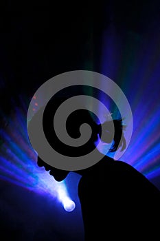 The silhouette of a person in disco rays in the smoke
