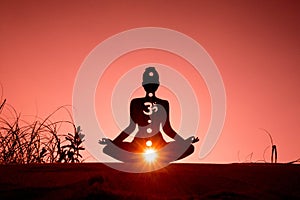 Silhouette of a person doing yoga with the root chakra symbol