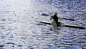 A silhouette of a person rowing a canoe