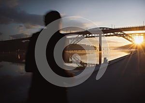 Silhouette of a person running at beautiful, early dawn under a bridge.