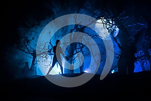 Silhouette of person standing in the dark forest. Horror halloween concept. strange silhouette in a dark spooky forest at night