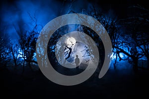 Silhouette of person standing in the dark forest with light. Horror halloween concept