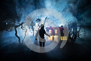 Silhouette of person standing in the dark forest with light. Horror halloween concept