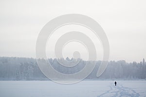 Silhouette of a person walking on a frozen lake on cold winter day photo