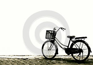 silhouette photo of a bicycle with a basket on the front, parked in the yard.  isolated white wall background.