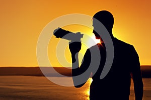 Silhouette of photo operator near sea at sunset
