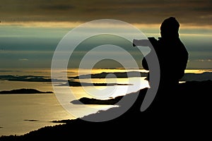 Silhouette of a photographer looking at sunset near Preikestolen, Norway