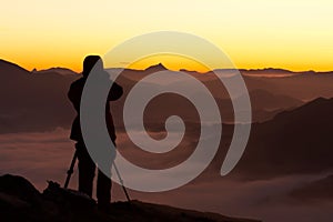 Silhouette of the photographer over a foggy mountain