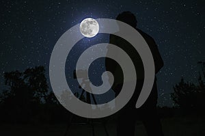 Silhouette of photographer standing with camera on tripod over Night sky with star background