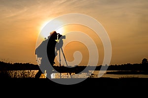 Silhouette photographer in sunset background