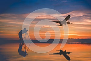 Silhouette photographer take photo and silhouette plane fly on s