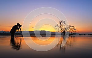 Silhouette photographer taken alone tree in the lake,