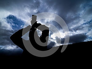 Silhouette of a photographer taking a picture with a camera and a zoom lens