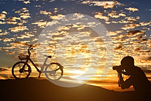 Silhouette of photographer taking pictures a bicycle at sunset