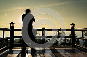 Silhouette photographer on the wooden roof with sunset time in t