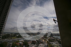 Silhouette picture of construction rope access worker wearing a hard hat, full body safety harness working at height, abseiling photo