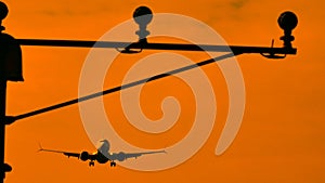 Silhouette of plane landing, runway lights, orange effect