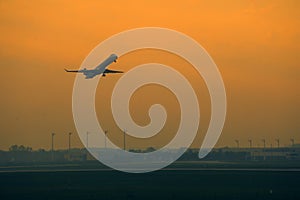 Silhouette of plane taking off, orange sky