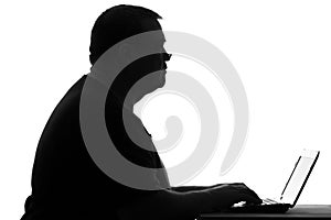 Silhouette of a plump man working at a laptop