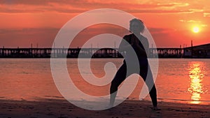 Silhouette of plump woman doing sports exercises on beach