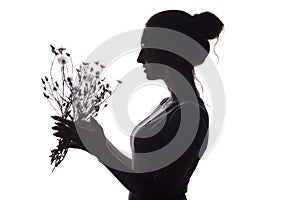 Silhouette pof a beautiful girl with a bouquet of dry dandelions, the face profile of a dreamy young woman on a white isolated