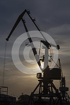 A silhouette of port cranes at sunset