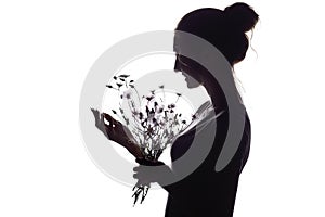 Silhouette portrait of a beautiful girl with a bouquet of dry dandelions, the face profile of a dreamy young woman on a white