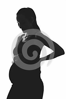 Silhouette portrait of pregnant woman on white background with hands on belly, vertical image