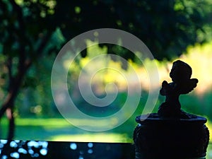 Silhouette of a praying angel against the background of an august evening