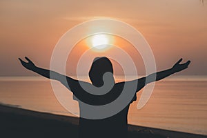 Silhouette of praying hands with God facing the sky at sunrise morning on the beach, Faith in religion and belief in God.