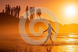 Silhouette of pregnant woman at beach with bright sunrise or sunset tones