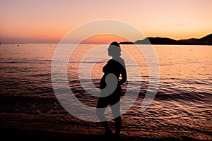 Silhouette of a pregnant woman on the seashore. Expectant mother expecting a baby