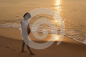 Silhouette of a pregnant woman walking on the beach