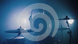 Silhouette of professional drummer plays a drums in smoky studio, slow motion