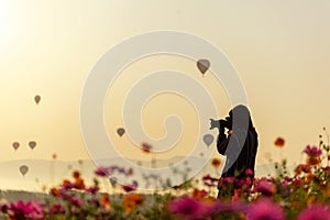 Silhouette professional woman photographer holding camera for take a photo balloon in cosmos meadow nature