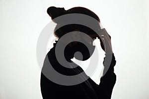 Silhouette profile of young woman thinking in protective mask on white studio background, figure of pensive girl, concept health