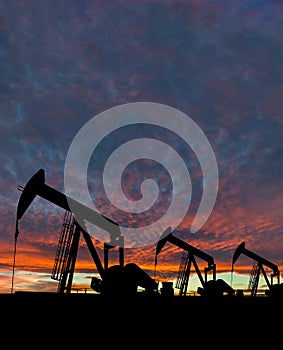 Silhouette of pumpjack against a dramatic sky