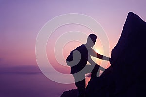 Silhouette purple of man climbing rock, Photographer on the mountain at sunrise