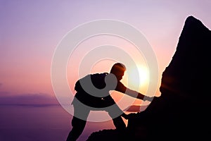 Silhouette purple of man climbing rock, Photographer on the mountain at sunrise
